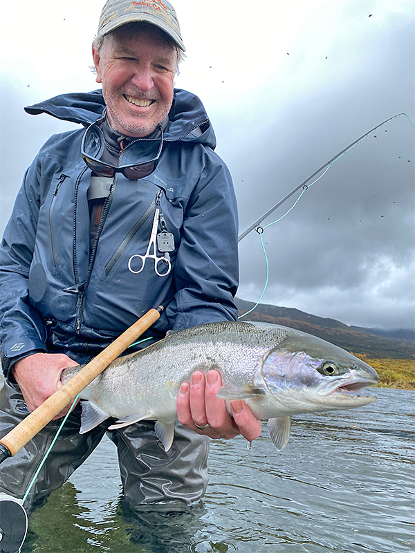 Pat Pendergast holding a wild steelhead while wearing the Skwala RS Jacket