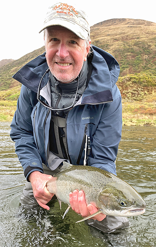 Pat Pendergast holding a wild steelhead while wearing the Skwala RS Jacket