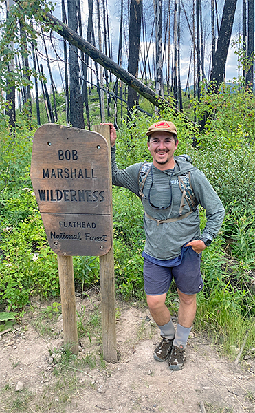 Mikey Kaplan standing at the Bob Marshall Wilderness sign
