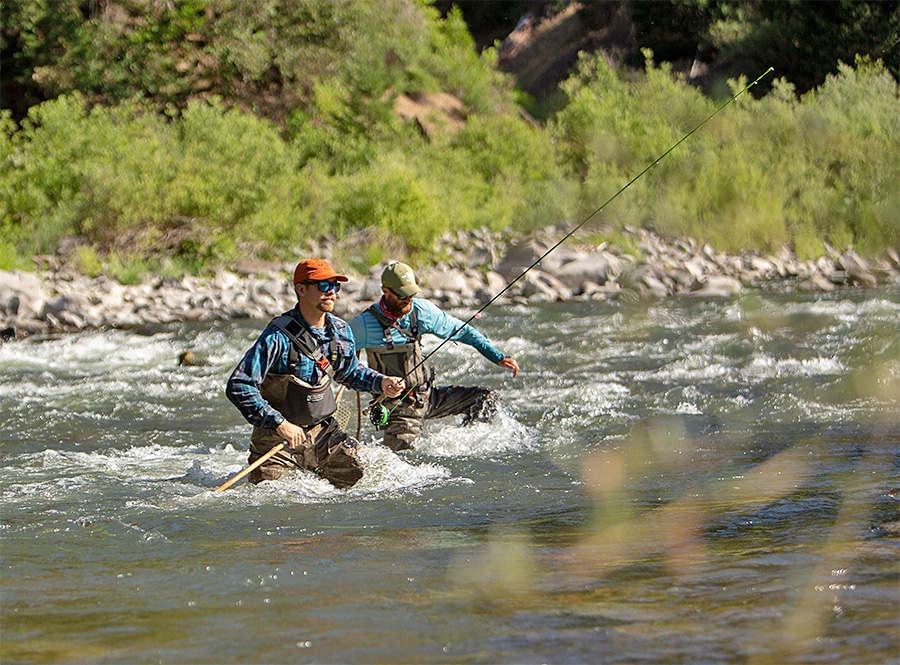 Anglers crossing the river using a wading staff