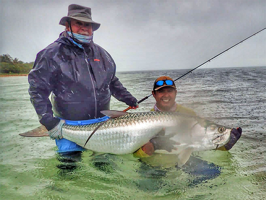 Guide holding tarpon on a rainy day