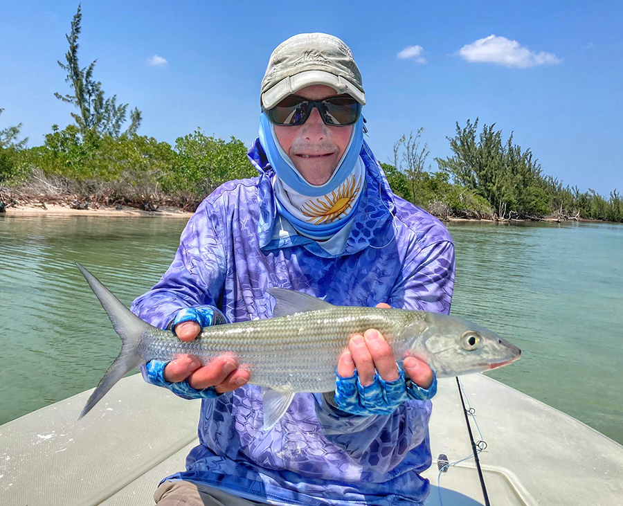 Angler sitting in skiff and holding a bonefish at ESB Lodge