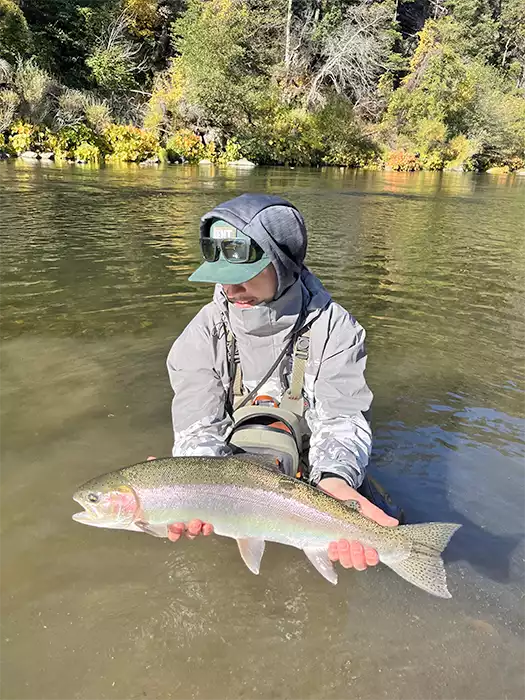 Joel Crandall in the water holding a rainbow trout