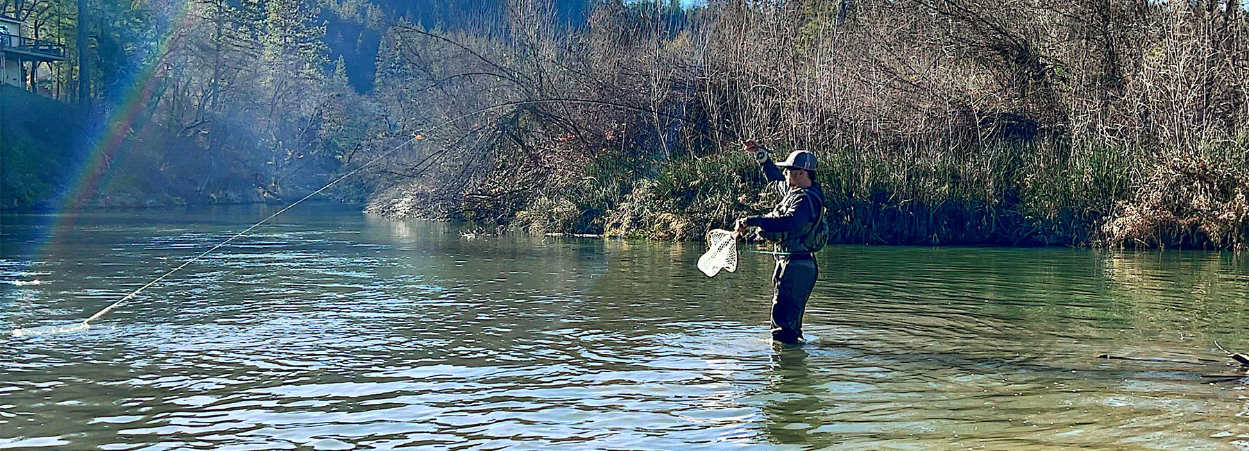 Joel Crandall fighting a fish while wading