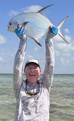 Angler holding a permit over his head at ESB Lodge