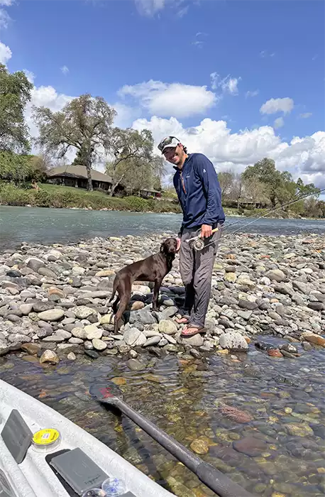 Preston Wedel and his dog standing on a gravel bar
